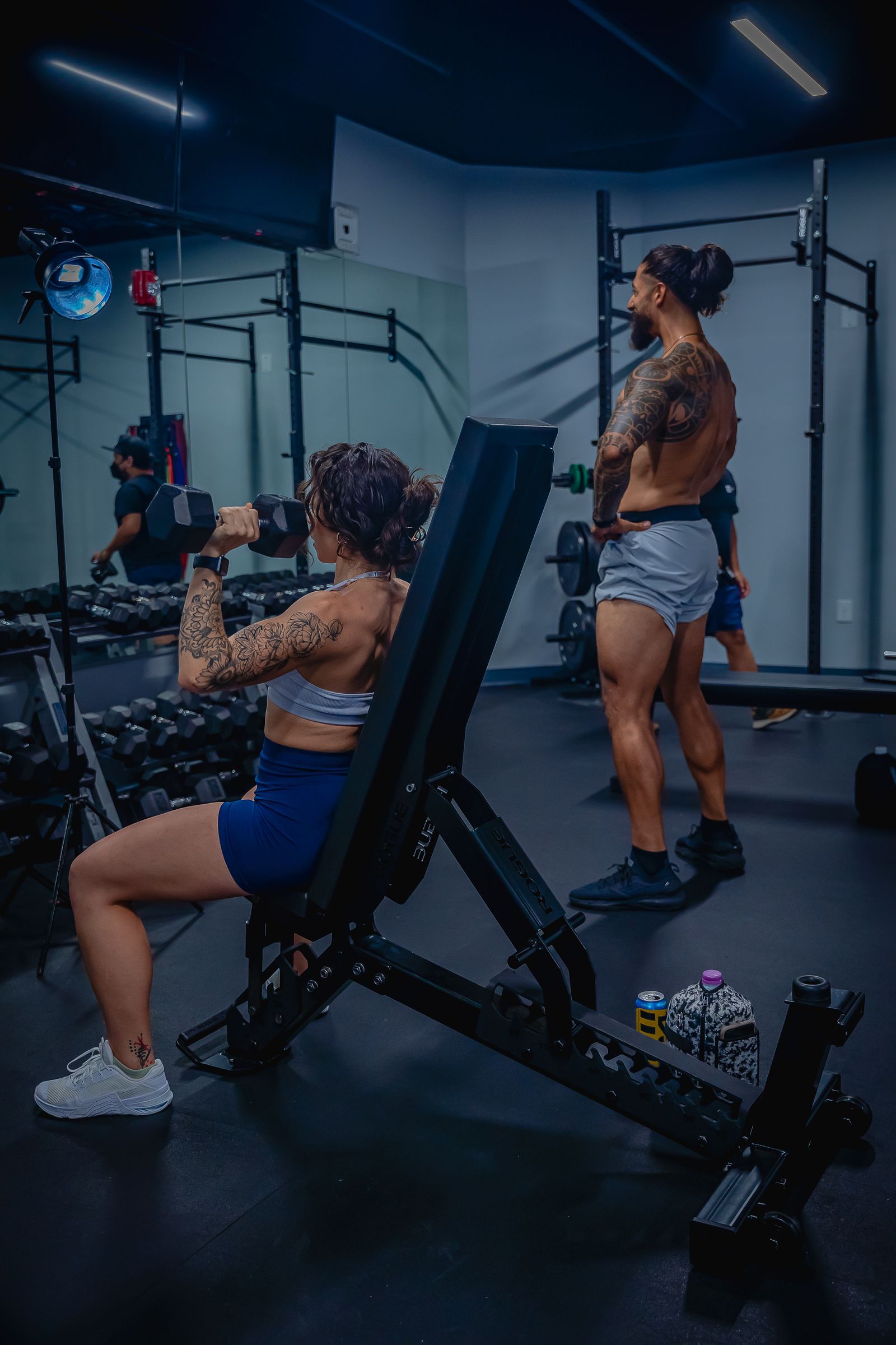 Two people strength training with dumbbells in a gym