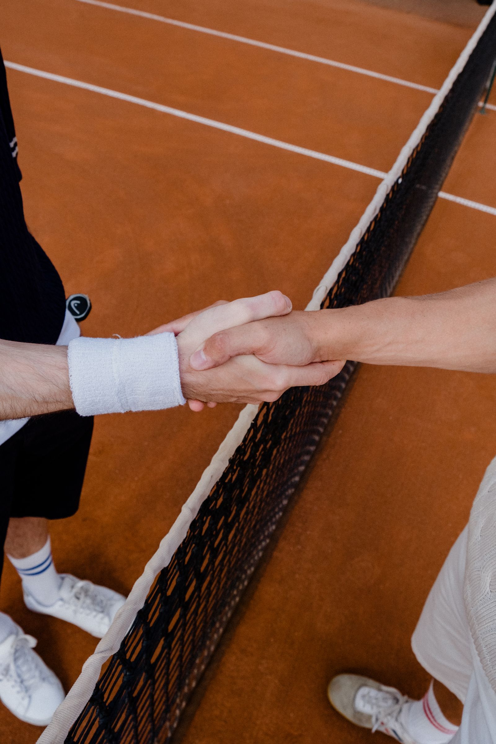 Two tennis players shaking hands across the net after a match